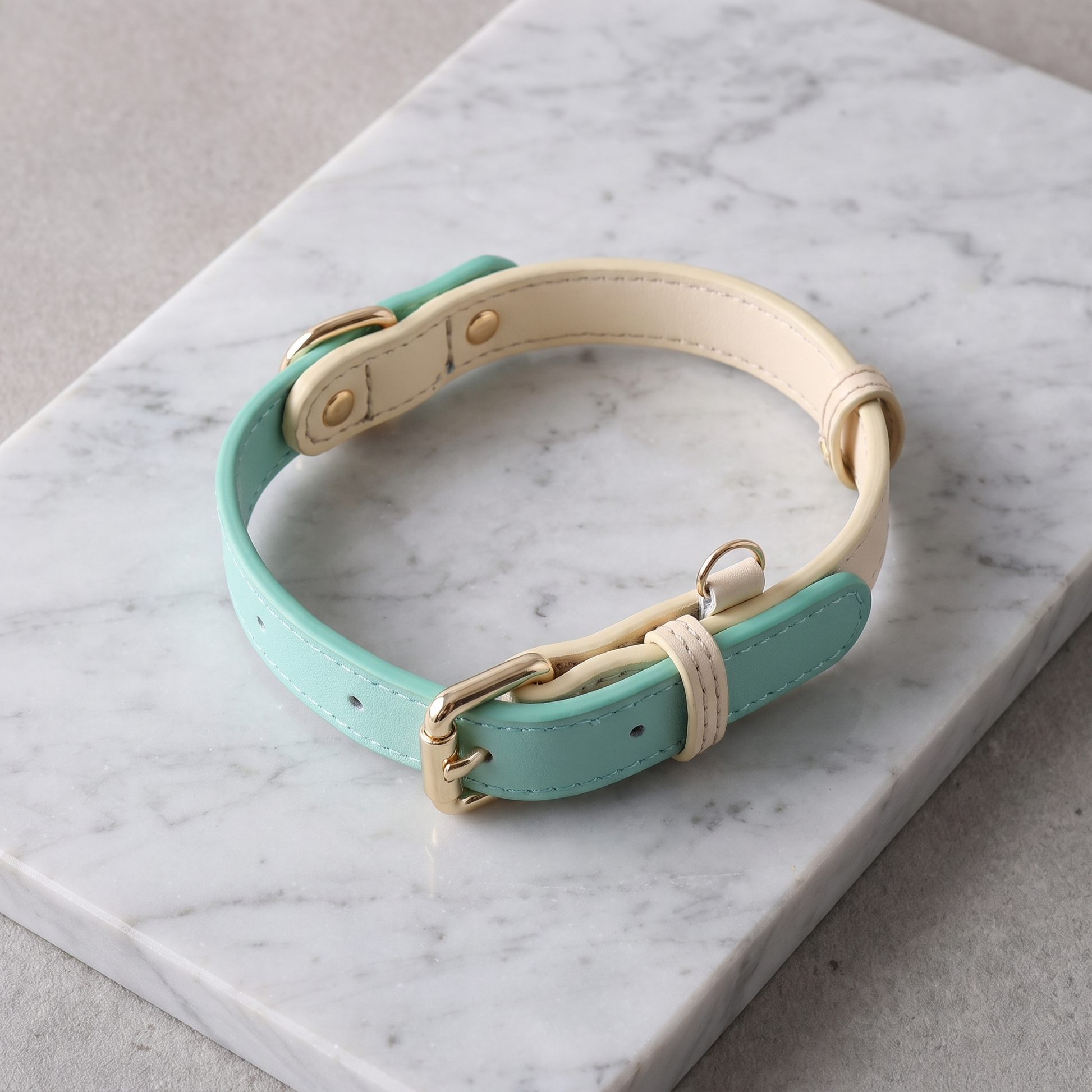 Genuine leather dog collar laid in an S-curve on pale grey marble, shot from above