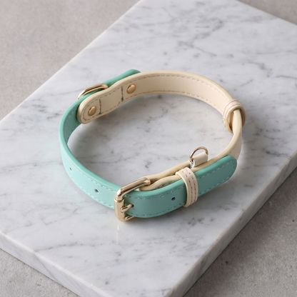 Genuine leather dog collar laid in an S-curve on pale grey marble, shot from above